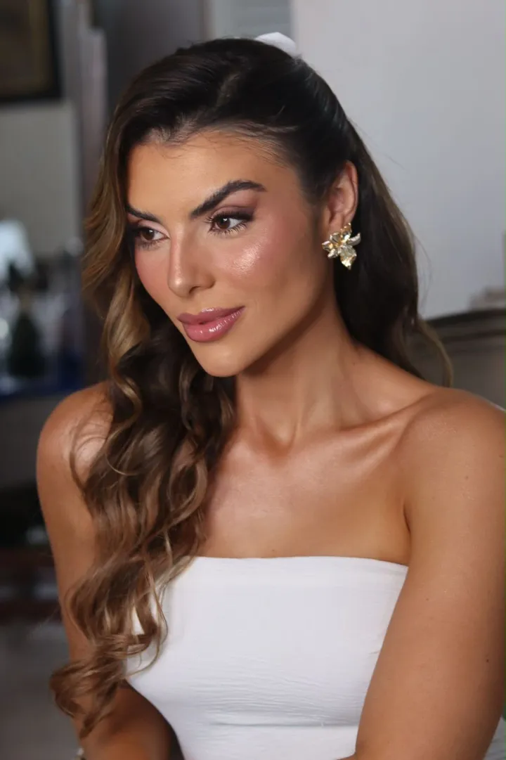 Cliente de vestido branco tomara que caia, com o colo e os ombros bronzeados.